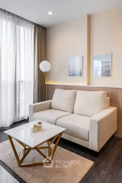 Modern living room with elegant sofa, stylish decor, and natural light from large windows.