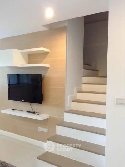 Modern interior with stylish staircase and wall-mounted TV in a contemporary home.