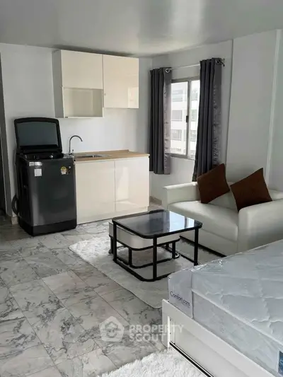 Modern studio apartment with sleek marble flooring and compact kitchen area.