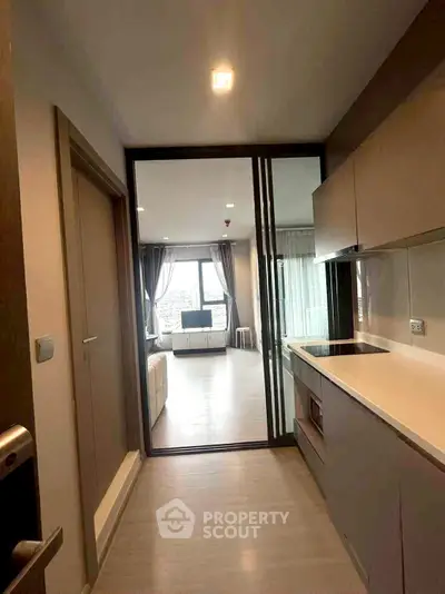 Modern apartment with sleek kitchen and spacious living area, featuring large windows and contemporary design.