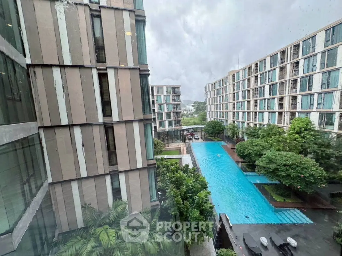 Modern apartment complex with large swimming pool and lush greenery