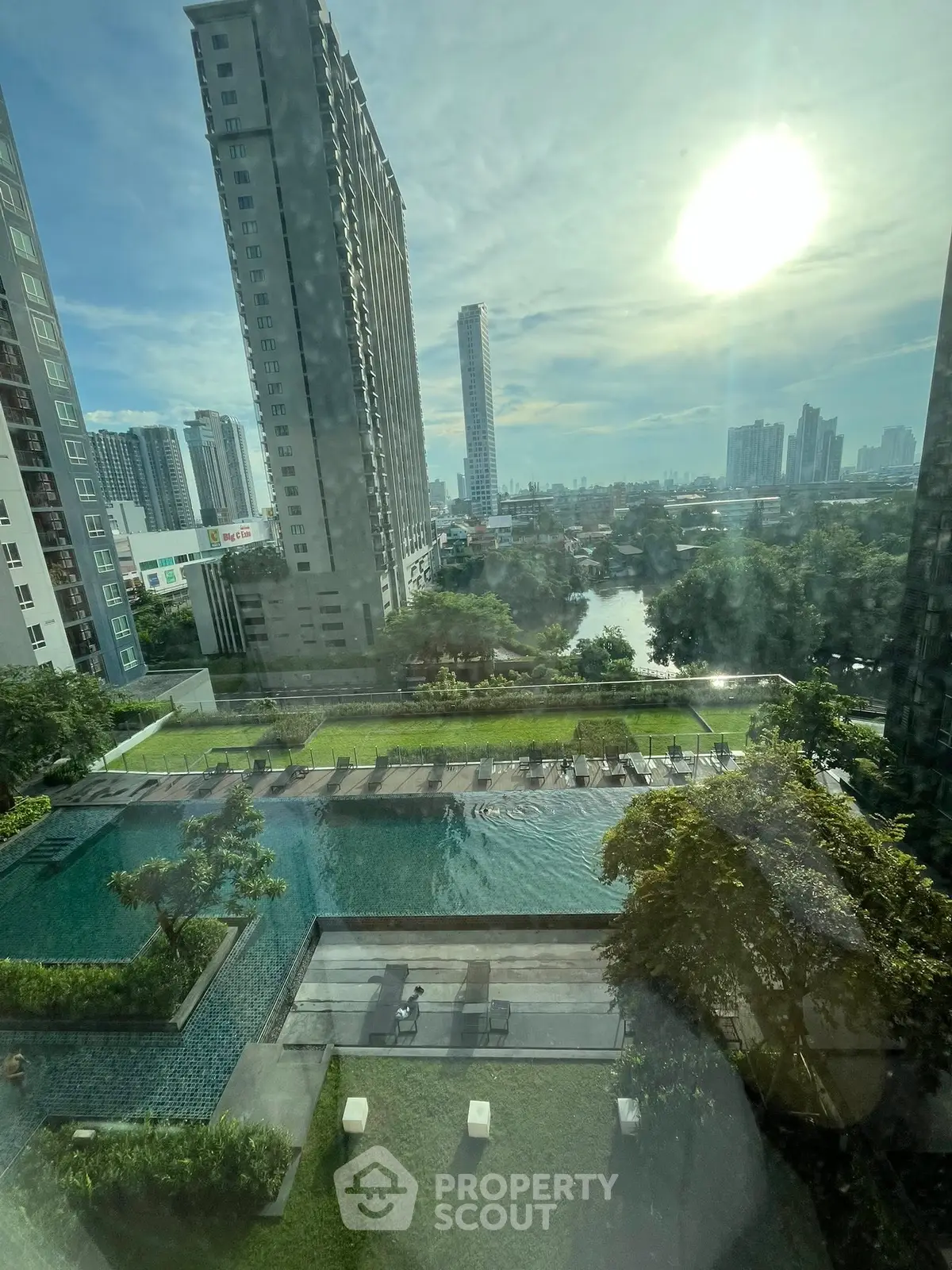 Stunning cityscape view from high-rise apartment with pool and lush greenery.