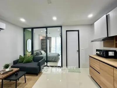 Modern open-plan living room with sleek kitchen and cozy bedroom view.