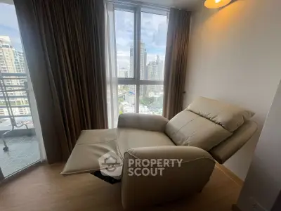 Cozy corner with recliner chair and city view from high-rise apartment window.