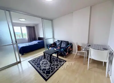 Modern studio apartment with sliding glass doors, cozy living area, and natural light.