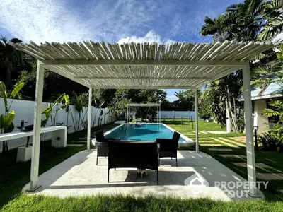 Luxurious outdoor pool area with modern pergola and lush garden, perfect for relaxation and entertainment.