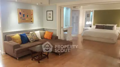 Spacious open-plan living room and bedroom with modern decor and cozy seating area.