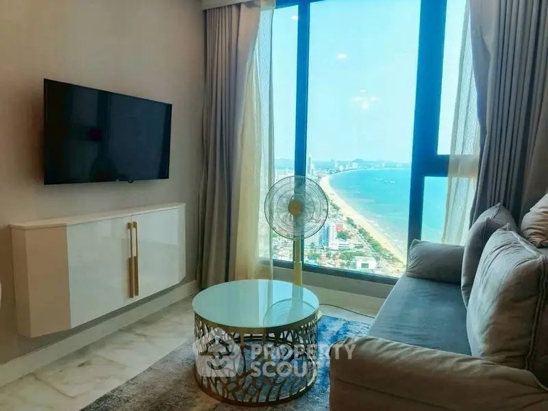 Modern living room with stunning ocean view, elegant decor, and wall-mounted TV.