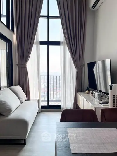 Modern living room with floor-to-ceiling windows and city view, featuring elegant decor and natural light.