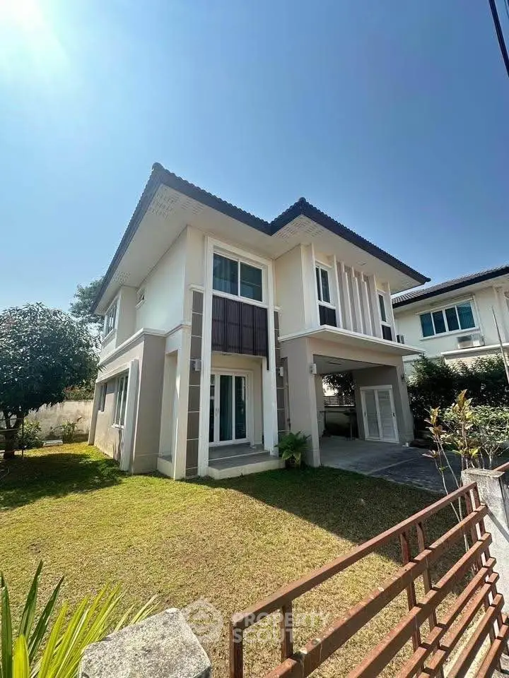 Modern two-story house with spacious garden and sleek design under clear blue sky.