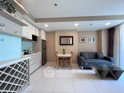 Modern living room with sleek kitchen, stylish furniture, and ample natural light in a contemporary apartment.