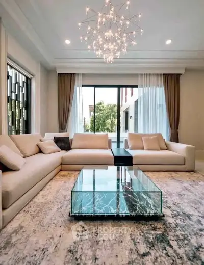 Luxurious living room with elegant chandelier and modern glass coffee table