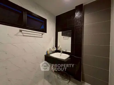 Modern bathroom with sleek black and white design, featuring a stylish sink and elegant wall tiles.