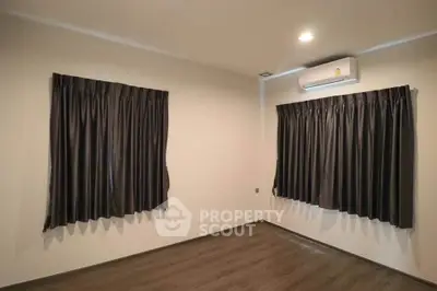 Spacious empty room with dark curtains and air conditioning, perfect for customization.