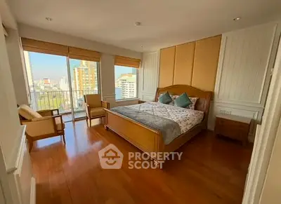 Spacious bedroom with wooden flooring and city view balcony in modern apartment