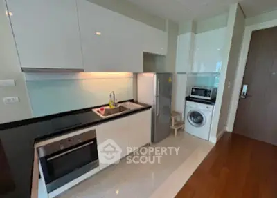 Modern kitchen with sleek cabinetry, built-in oven, and washing machine in a stylish apartment.
