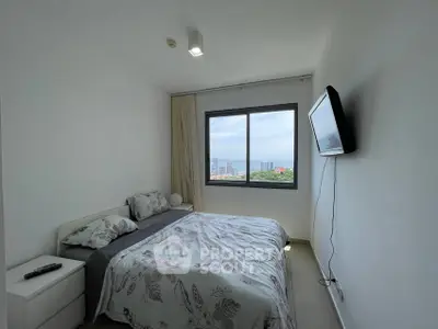 Modern bedroom with ocean view and wall-mounted TV in a high-rise apartment.