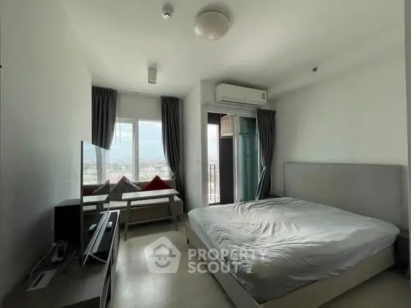 Modern bedroom with balcony and city view, featuring minimalist decor and natural light.