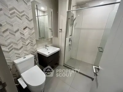 Modern bathroom with glass shower and sleek fixtures in contemporary apartment.