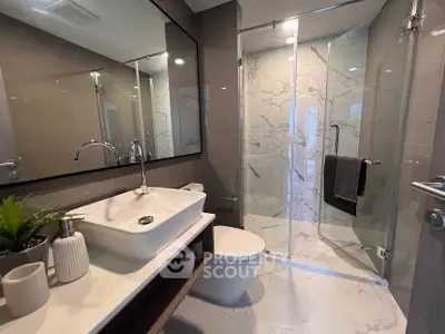 Modern bathroom with sleek design, featuring a glass shower and elegant fixtures.