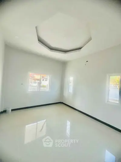 Spacious unfurnished room with large windows and unique ceiling design