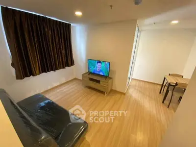 Modern living room with wooden flooring, cozy sofa, and flat-screen TV, perfect for relaxation.