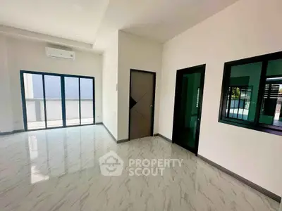 Spacious modern living room with large windows and balcony access, featuring sleek marble flooring.