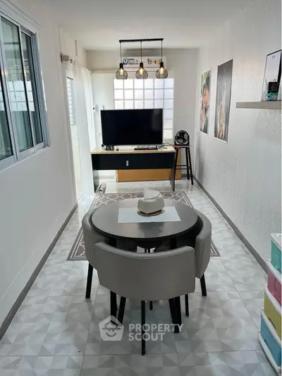 Modern living room with stylish decor and dining area, featuring a sleek TV setup and contemporary lighting.