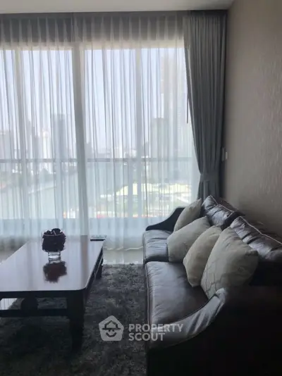 Chic living room with leather sofa and city view through large windows.