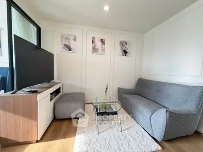 Modern living room with stylish gray sofa and large TV, perfect for relaxation.