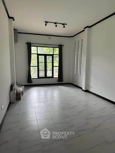 Spacious empty room with large window and tiled floor, ideal for customization.