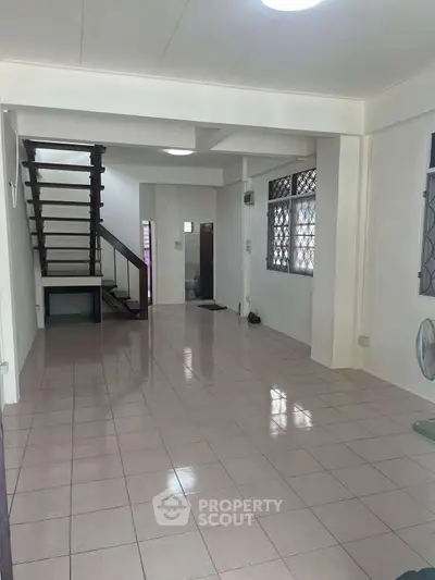 Spacious open-plan living area with tiled flooring and staircase, ideal for modern living.