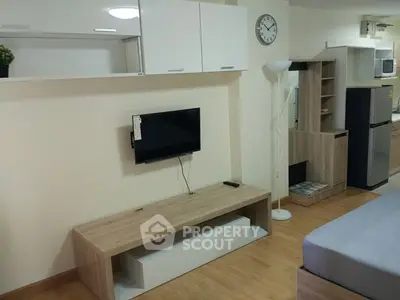 Modern studio apartment with sleek furniture and wall-mounted TV, featuring a compact kitchen area.