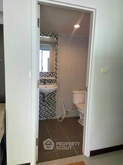 Compact bathroom with modern fixtures and mosaic tile accents