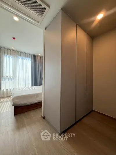Spacious bedroom with large windows and ample natural light, featuring modern wardrobe and elegant flooring.