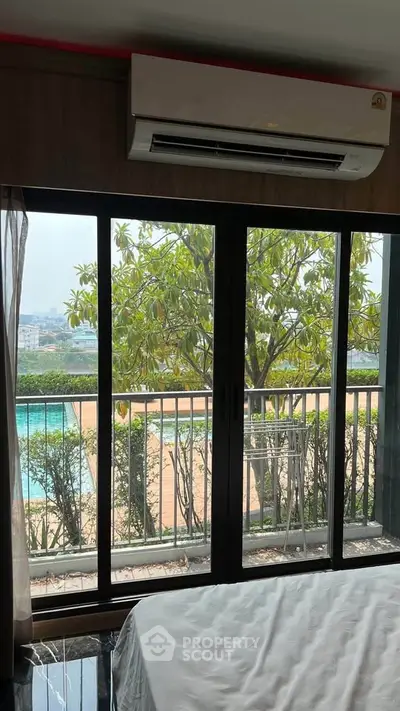 Spacious bedroom with large windows offering a stunning pool view and balcony access.