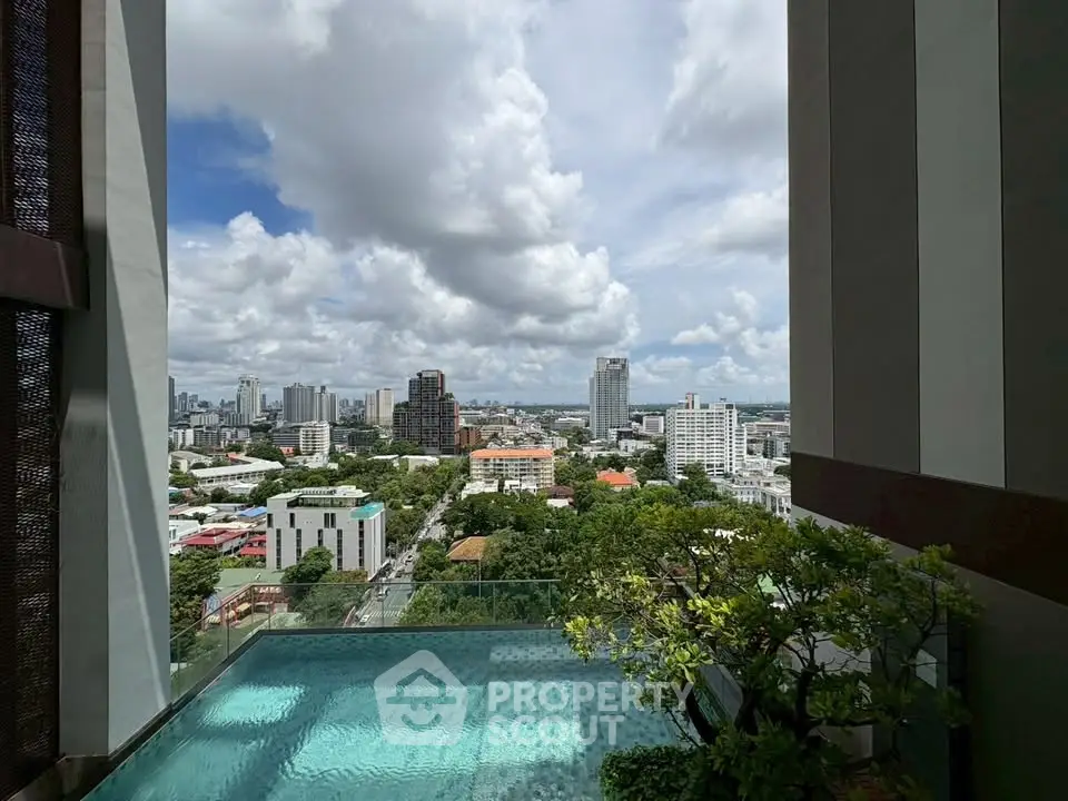 Stunning cityscape view from a high-rise balcony with a pool and lush greenery.
