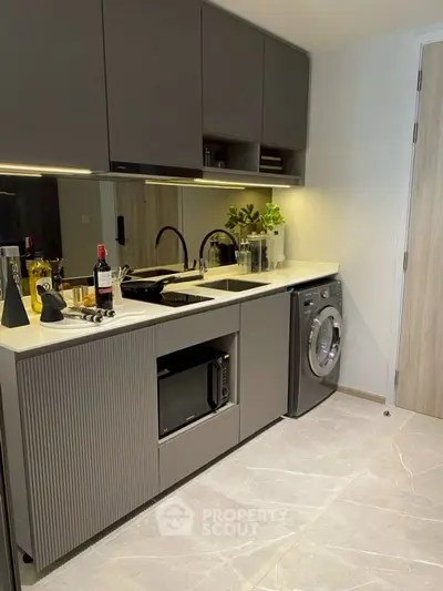 Modern kitchen with sleek cabinetry, built-in appliances, and washing machine in stylish apartment.