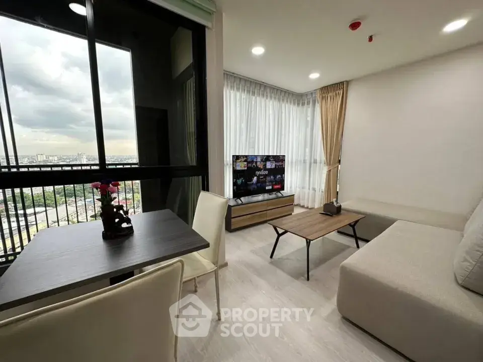 Modern living room with city view, featuring sleek furniture and large windows for natural light.