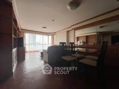 Spacious living room with wooden flooring and large windows in a modern apartment.