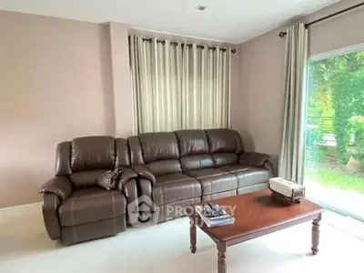 Spacious living room with leather sofa and garden view, perfect for relaxation.