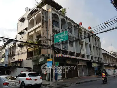 Urban street view of a multi-story building with retail space in bustling city area.