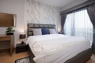 Modern bedroom with stylish decor and large window offering natural light.