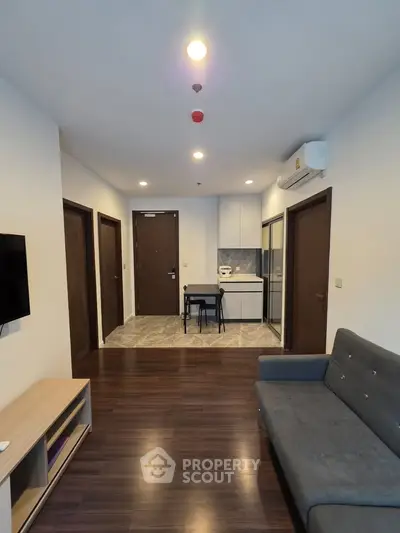 Modern apartment interior with open kitchen and cozy living area, featuring sleek wooden flooring and stylish decor.