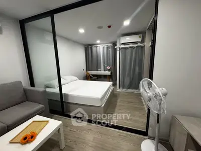 Modern studio apartment with glass partition, cozy living area, and stylish bedroom.