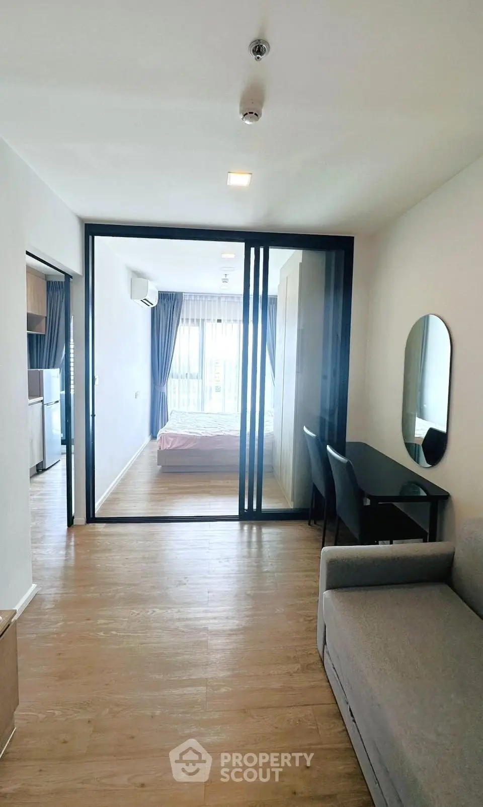 Modern apartment interior with open layout, featuring a cozy living area and stylish bedroom separated by glass doors.