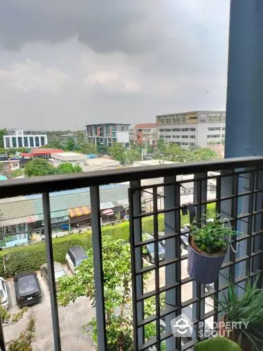 Cozy balcony with urban view, featuring potted plants and overlooking a bustling neighborhood, perfect for relaxation and city living.