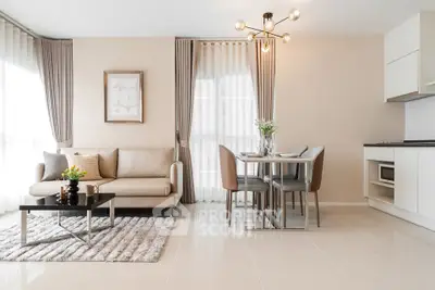 Modern living room with elegant decor and open kitchen layout, featuring stylish furniture and natural light.
