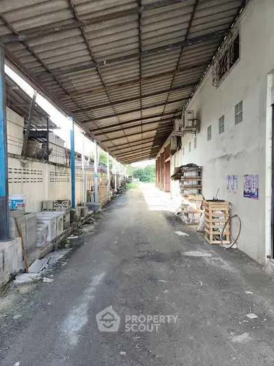 Industrial warehouse exterior with covered pathway and storage area