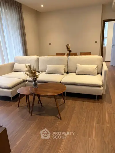 Modern living room with stylish beige sofa and wooden coffee tables, perfect for cozy gatherings.